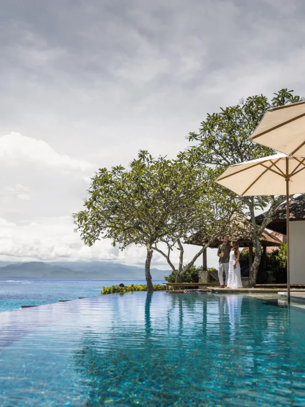 Infinity pool with linen umbrellas and cliff-edge ocean view at Lago Beach House Nusa Lembongan
