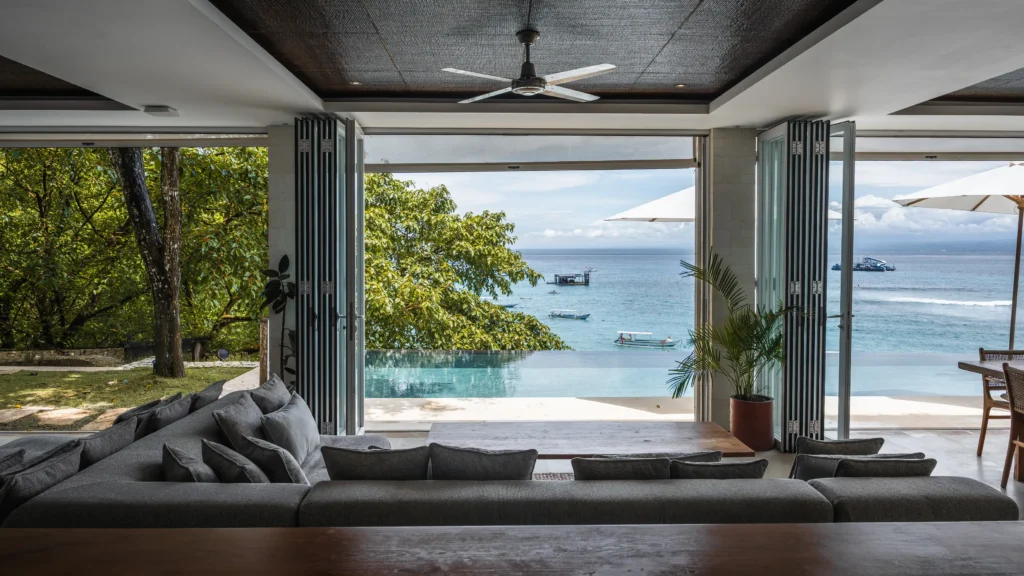 Living room view through bifold doors to the infinity pool, ocean and jukungs at Lago Beach House