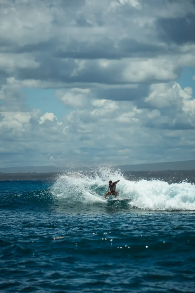 A surfer carves off the lip of a clean shoulder-high wave, spray flying, off the coast of Nusa Lembongan, Bali